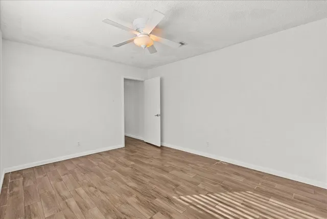 an empty room with wooden floor and windows