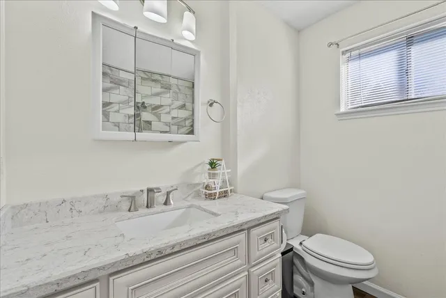 a bathroom with a granite countertop toilet sink and mirror