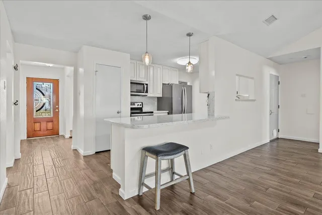 a kitchen with kitchen island white cabinets and stainless steel appliances