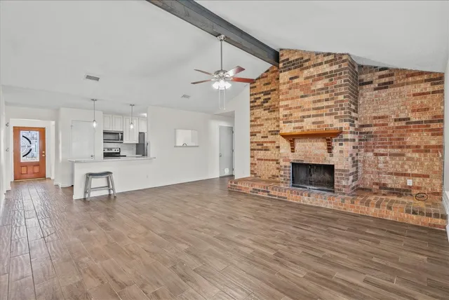 a view of empty room with wooden floor and fireplace