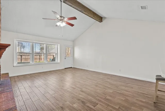 a view of an empty room with wooden floor and a window