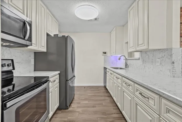 a kitchen with granite countertop a sink stainless steel appliances and cabinets