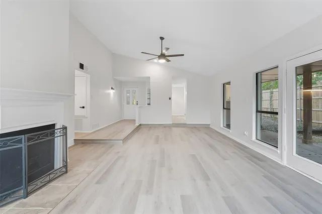 an empty room with wooden floor a ceiling fan and windows