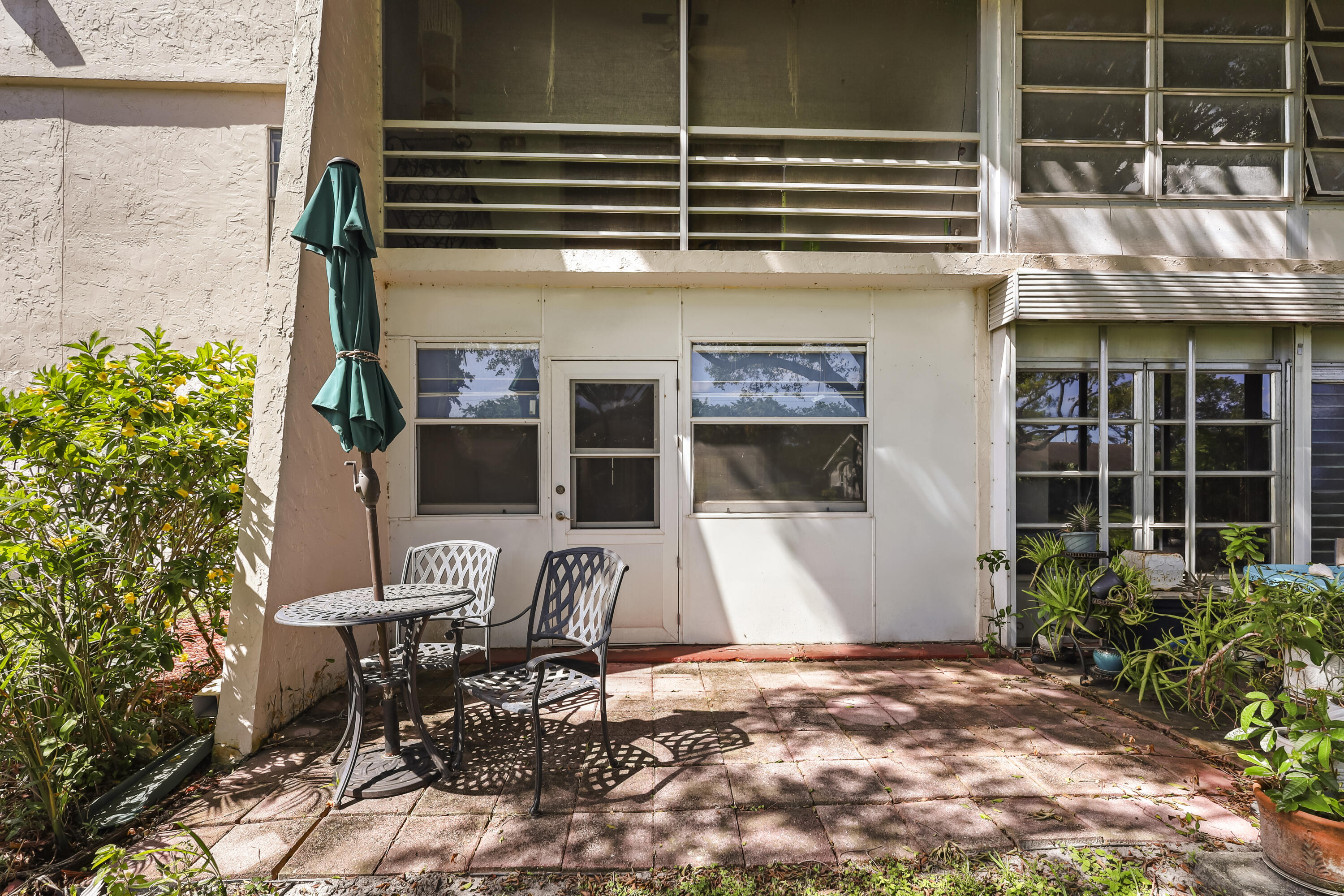 2500 Fiore Way, Unit 103 Delray Beach, FL 33445 - Photo 17 of 19 a view of a patio with table and chairs potted plants with wooden fence