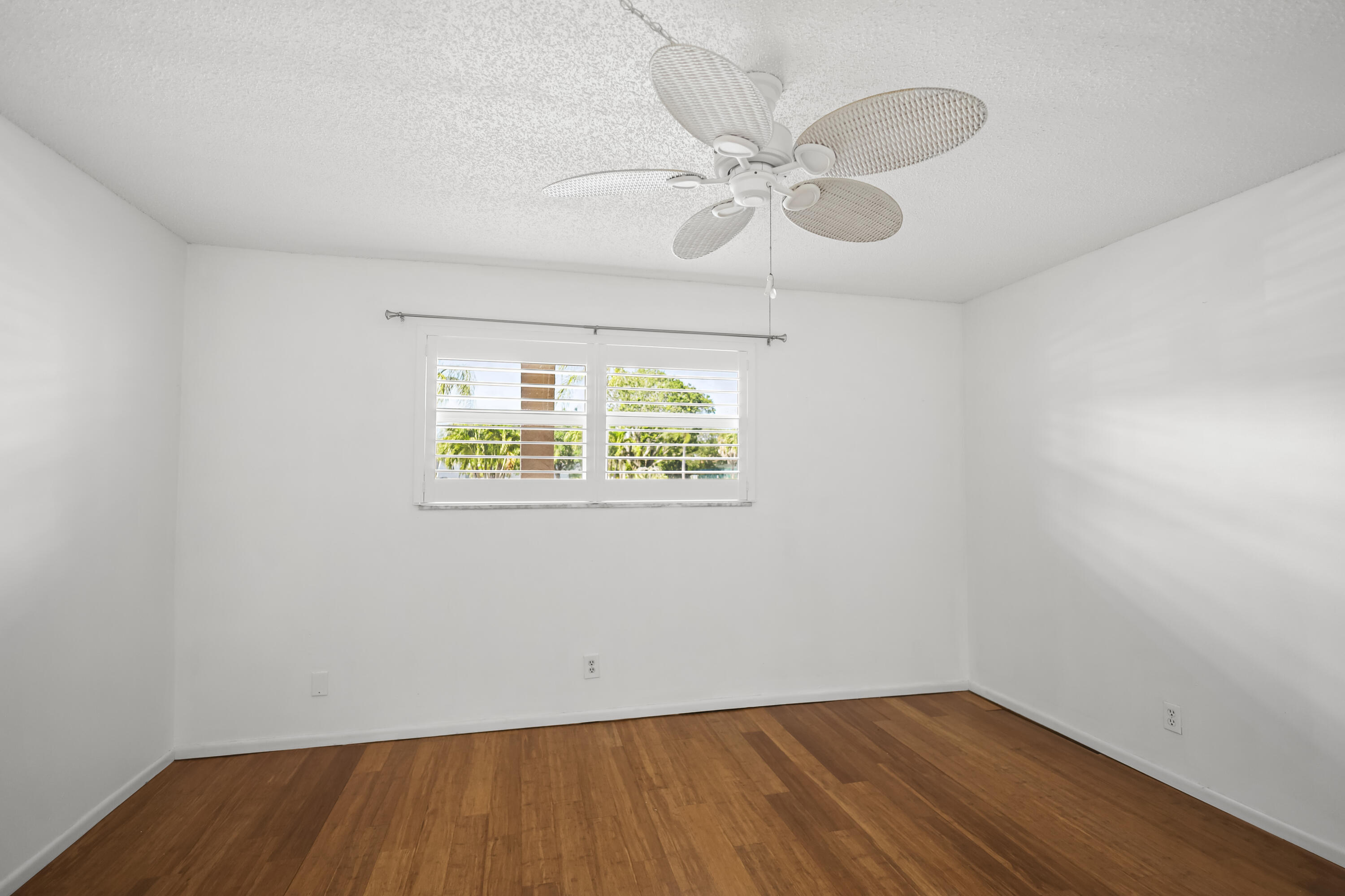 2500 Fiore Way, Unit 103 Delray Beach, FL 33445 - Photo 9 of 19 an empty room with wooden floor fan and windows