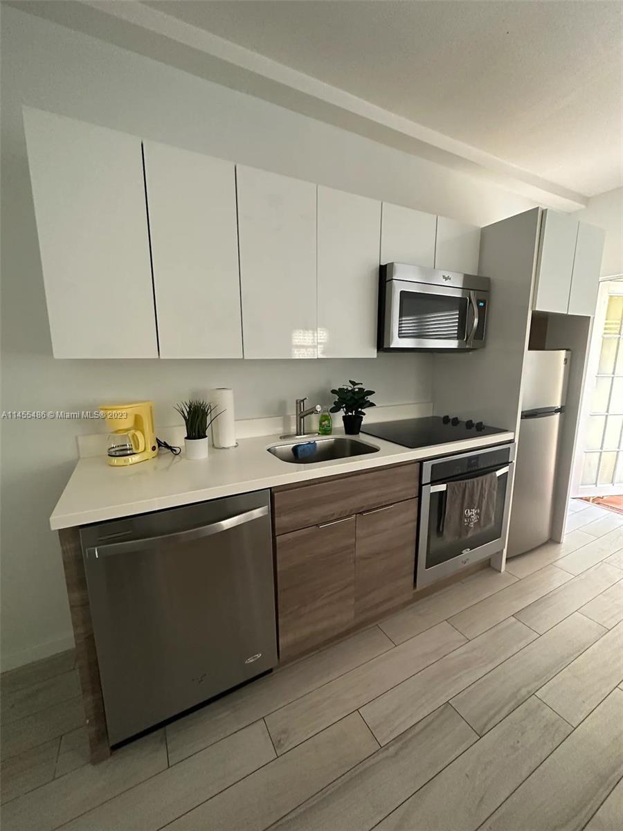 a kitchen with stainless steel appliances a sink a stove a microwave a refrigerator a sink and cabinets