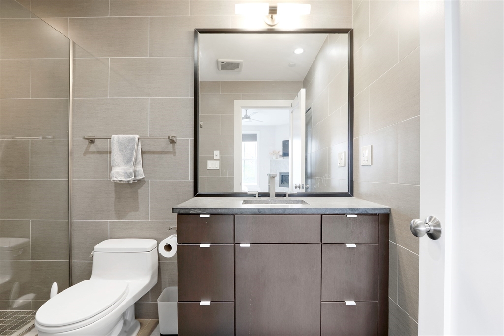 309 E Street, Unit 45 Boston, MA 02127 - Photo 13 of 33 a bathroom with a granite countertop sink a toilet and a mirror