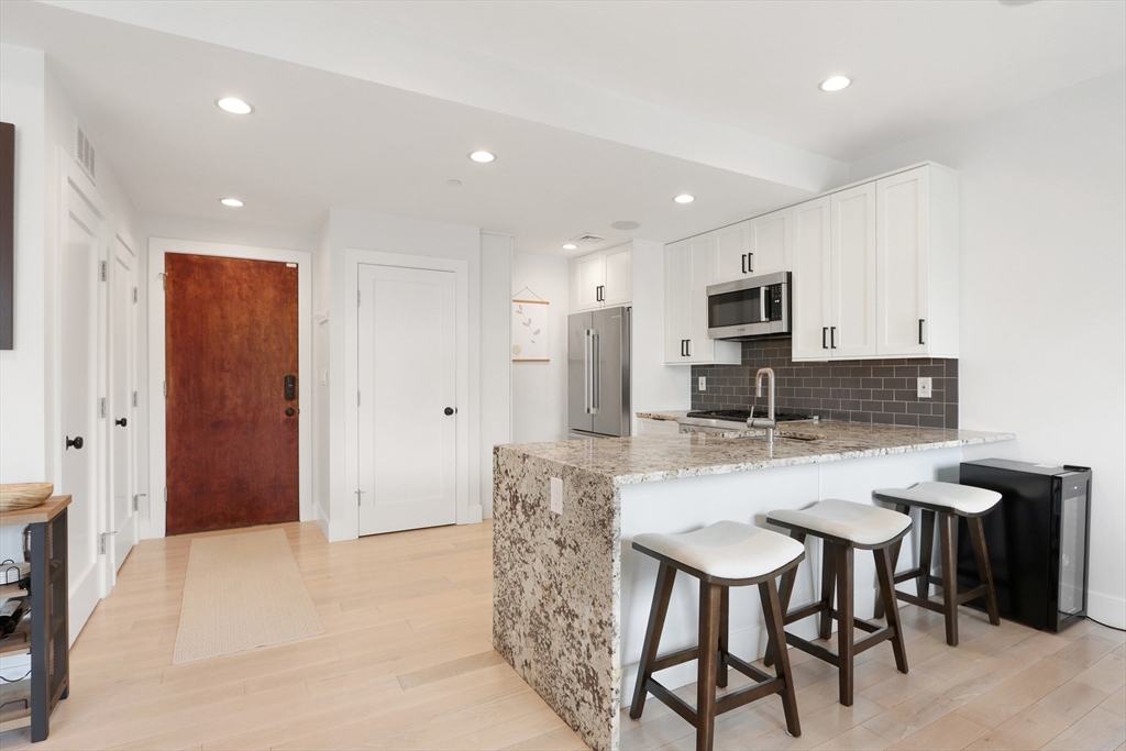 309 E Street, Unit 45 Boston, MA 02127 - Photo 9 of 33 a kitchen with kitchen island granite countertop a table and chairs in it
