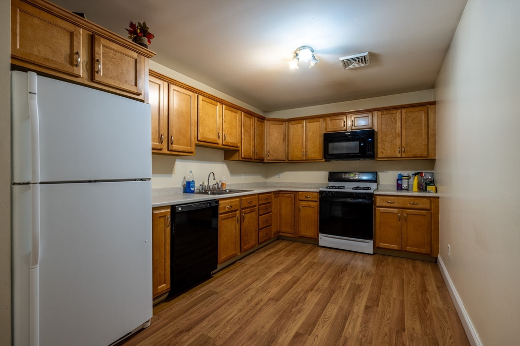 1556 North Main Street, Unit 10 Fall River, MA 02720 - Photo 7 of 30 a kitchen with stainless steel appliances granite countertop a refrigerator a stove top oven a sink with wooden cabinets and wooden floor