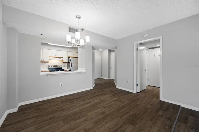a view of a room with wooden floor kitchen and chandelier