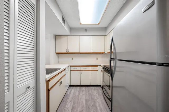 a kitchen with a sink a refrigerator and cabinets