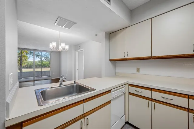 a kitchen with stainless steel appliances granite countertop a sink a stove white cabinets and a wooden floor