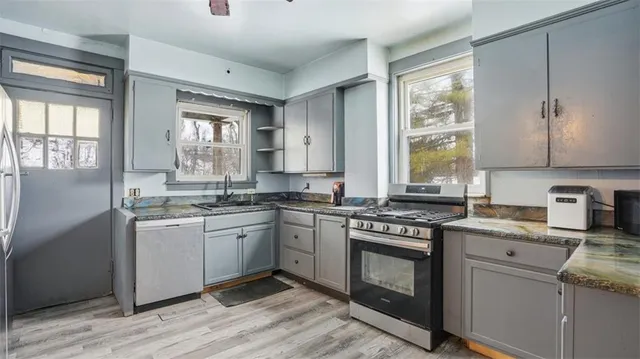 a kitchen with granite countertop stainless steel appliances a sink window and cabinets