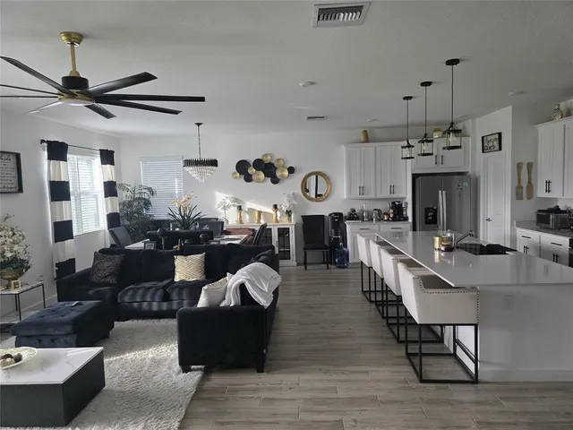 a living room with furniture kitchen view and a chandelier