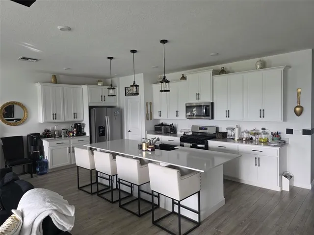 a kitchen with stainless steel appliances a stove a sink a oven a dining table and chairs