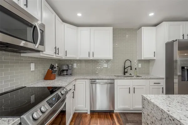 a kitchen with stainless steel appliances granite countertop a sink stove microwave and cabinets