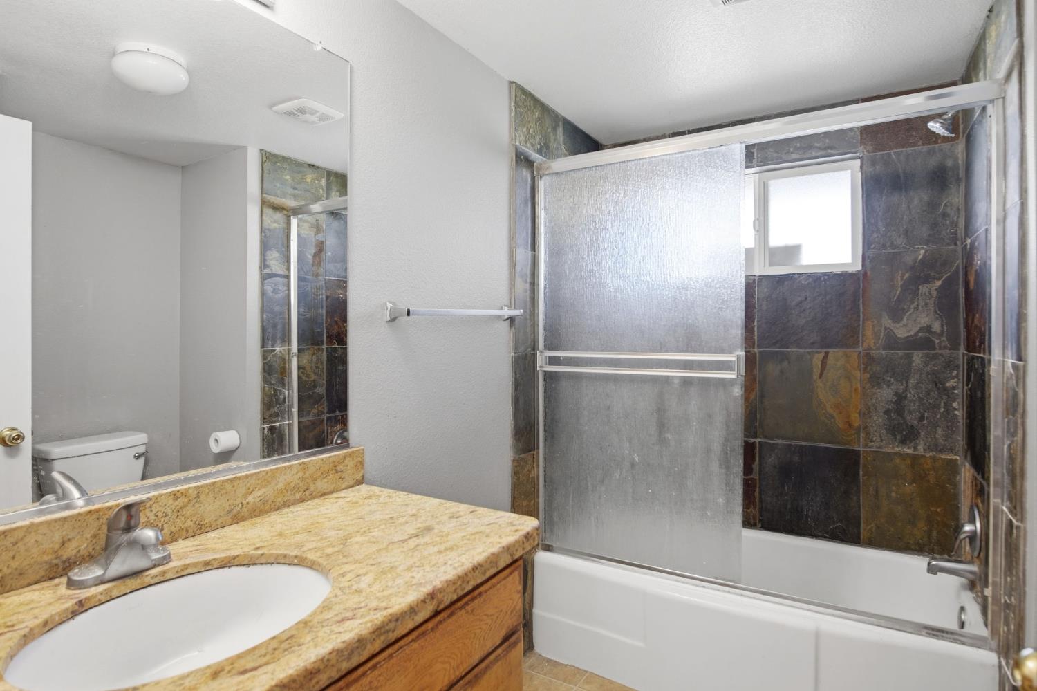 1409 Stonum Road Modesto, CA 95351 - Photo 14 of 40 a bathroom with a granite countertop bathtub shower sink and mirror