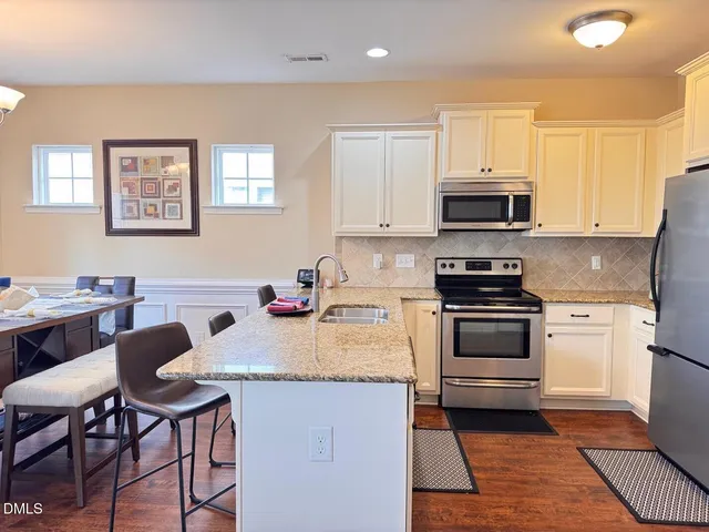 a kitchen with stainless steel appliances a stove top oven a sink dishwasher and white cabinets