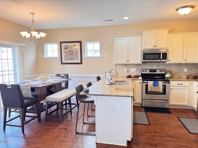 a kitchen with stainless steel appliances kitchen island granite countertop a stove a sink a dining table and chairs