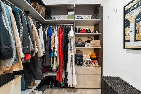 a view of walk in closet with clothes and shoes