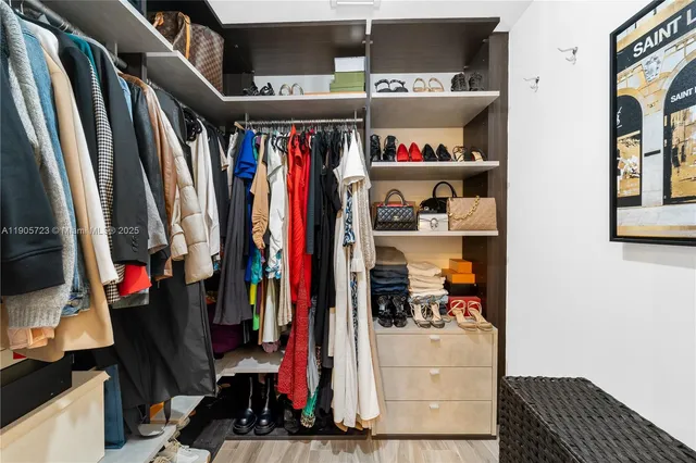 a view of walk in closet with clothes and shoes