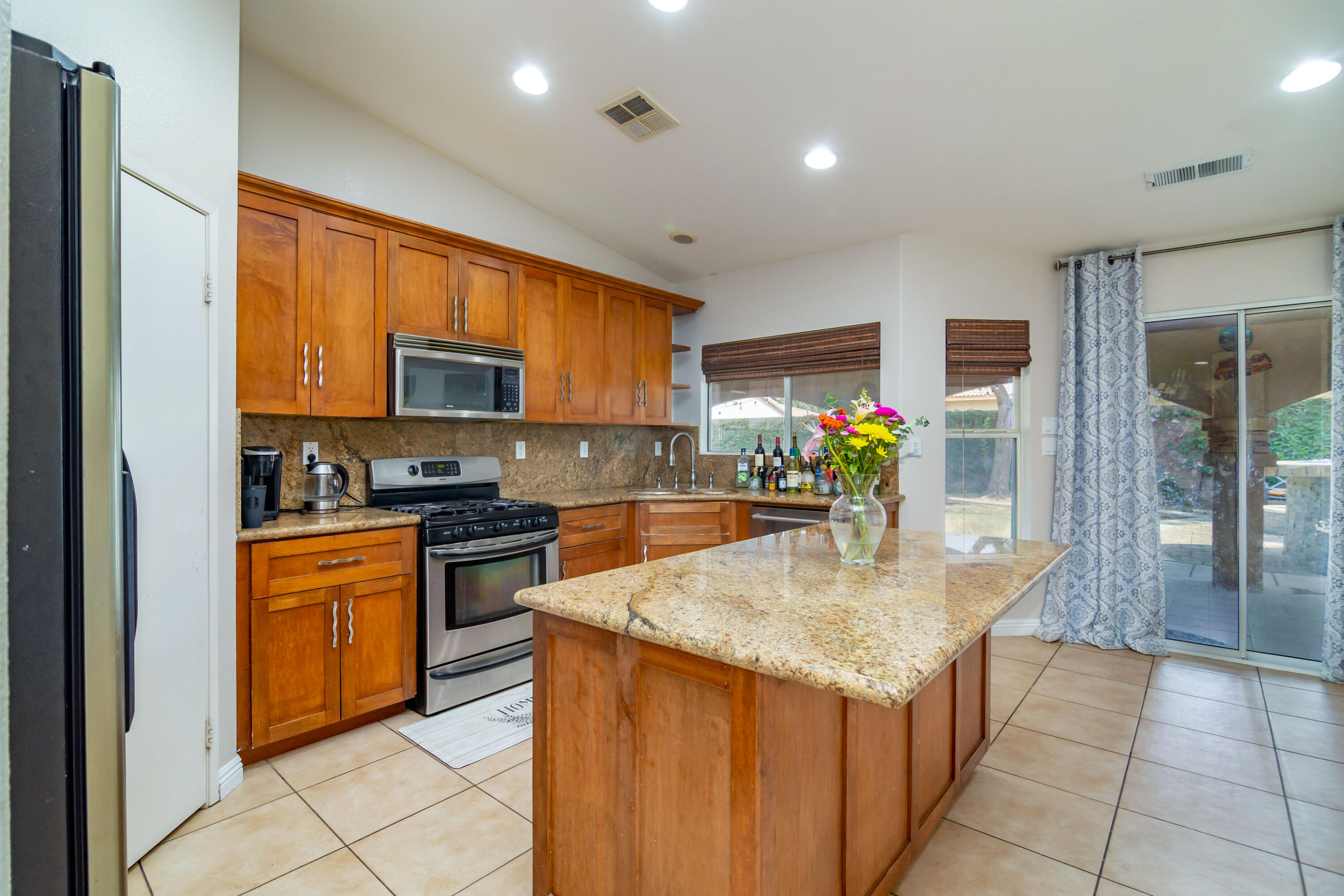83290 Antigua Drive Indio, CA 92201 - Photo 15 of 31 a kitchen with stainless steel appliances granite countertop a stove top oven a sink dishwasher and a refrigerator with wooden floor
