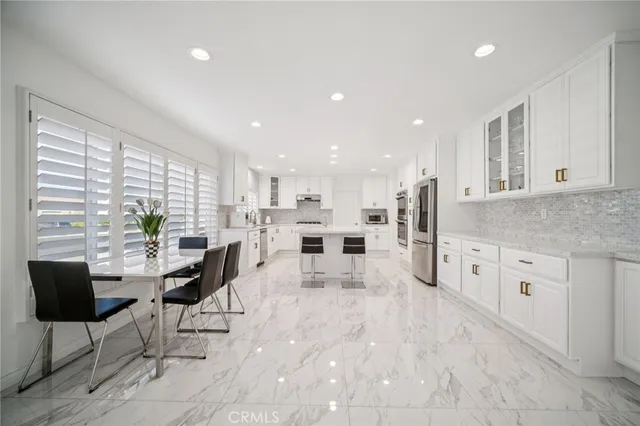 a room with stainless steel appliances kitchen island granite countertop a refrigerator and a stove top oven