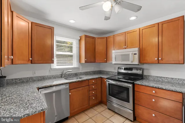 a kitchen with granite countertop stainless steel appliances a stove sink and cabinets