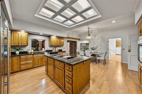 a kitchen with granite countertop a stove a sink dishwasher and a refrigerator with wooden floor