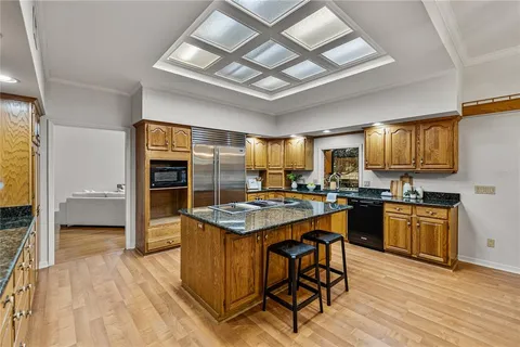a kitchen with stainless steel appliances granite countertop a kitchen island a stove a sink dishwasher a dining table and chairs with wooden floor