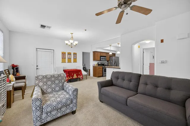 a living room with furniture kitchen view and a chandelier