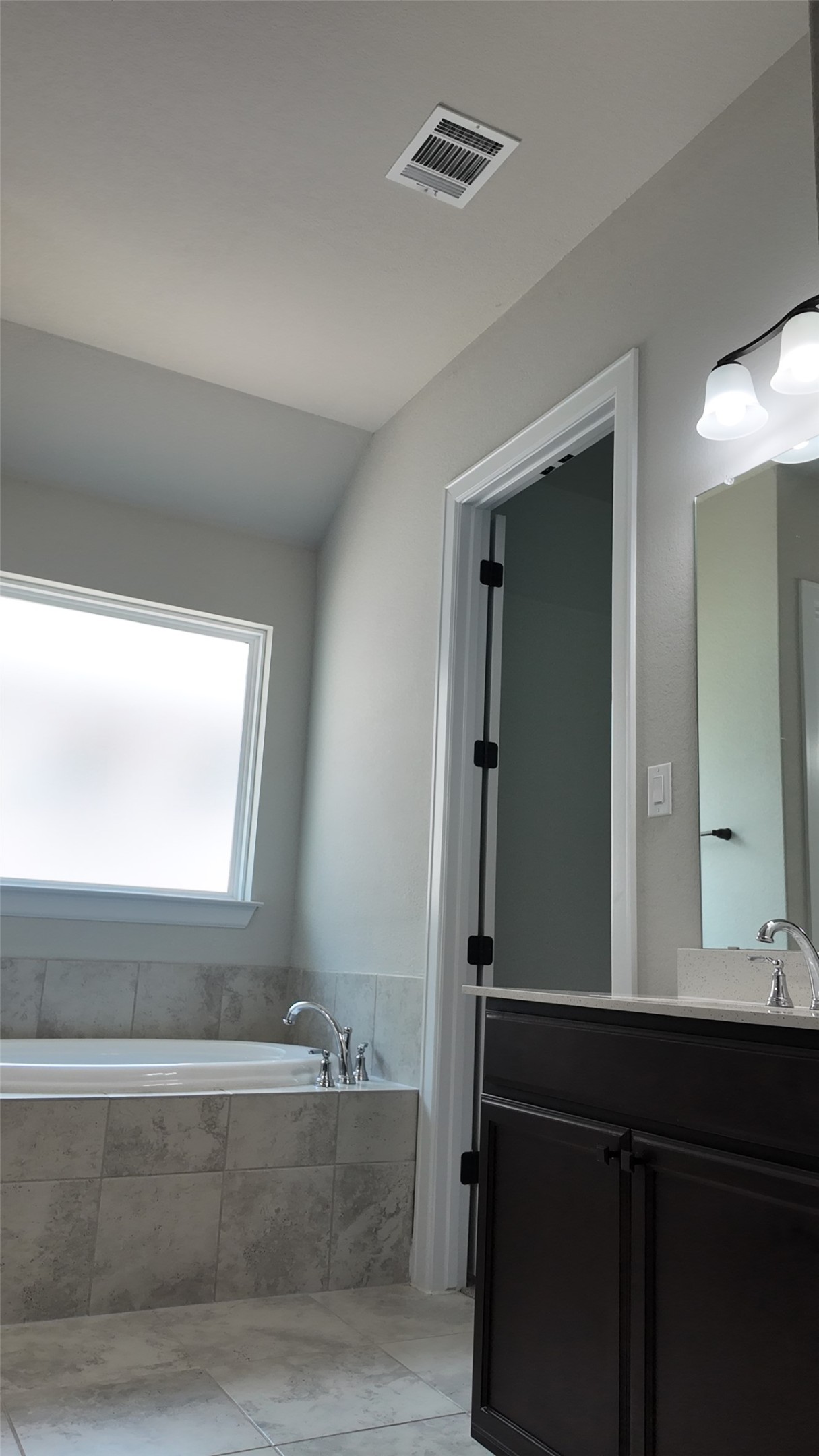 2320 Base Burner Path Leander, TX 78641 - Photo 18 of 24 A well-lit bathroom features a built-in soaking tub, tile flooring, and a vanity with a counter.
