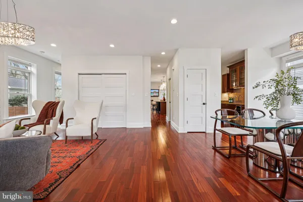 a kitchen with stainless steel appliances granite countertop a stove top oven a refrigerator a dining table and chairs with wooden floor