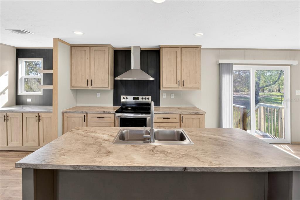 5570 Northeast 76th Avenue High Springs, FL 32643 - Photo 9 of 31 a kitchen with kitchen island granite countertop a sink a stove and a wooden floors