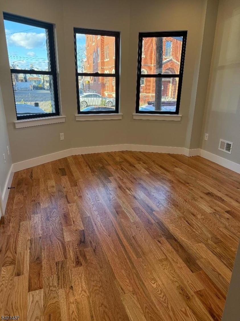76 Barbara Street, Unit 1 Newark, NJ 07105 - Photo 2 of 8 a view of an empty room with wooden floor and a window
