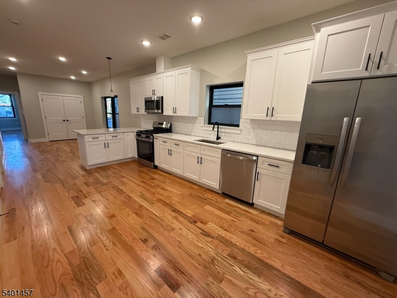 76 Barbara Street, Unit 1 Newark, NJ 07105 - Photo 4 of 8 a large kitchen with stainless steel appliances granite countertop a stove a sink dishwasher and a refrigerator with wooden floor