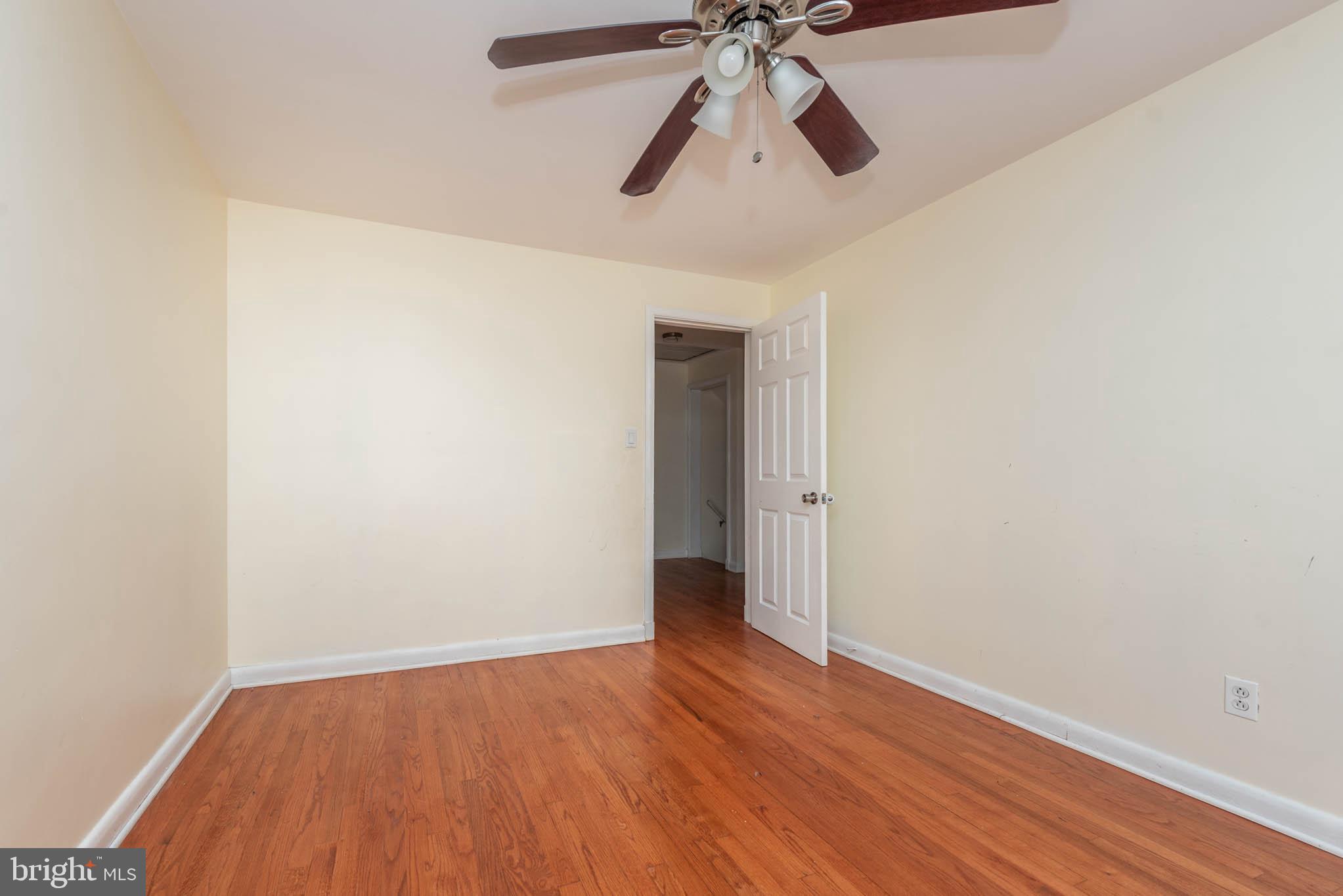6702 Queens Ferry Road Baltimore, MD 21239 - Photo 25 of 40 an empty room with wooden floor ceiling fan and hardwood floor