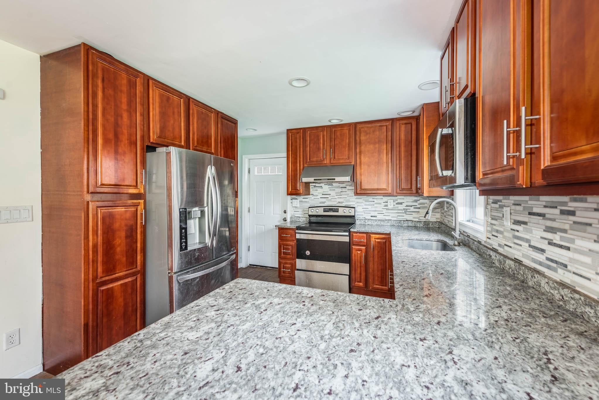 6702 Queens Ferry Road Baltimore, MD 21239 - Photo 8 of 40 a kitchen with granite countertop a refrigerator stove top oven a sink and dishwasher