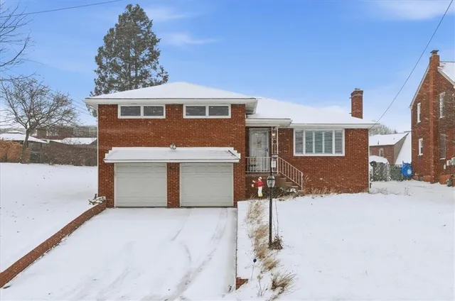 a front view of a house with a yard covered in snow