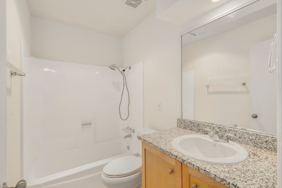 1008 Ridgeline Drive Round Rock, TX 78664 - Photo 23 of 30 a bathroom with a granite countertop sink a toilet and shower