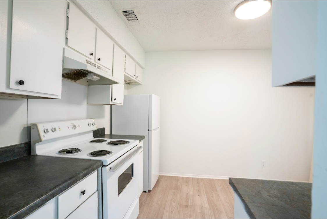 906 Silver Quail Lane Austin, TX 78758 - Photo 13 of 33 Kitchen with white appliances, under cabinet range hood, dark countertops, white cabinetry, and light wood finished floors