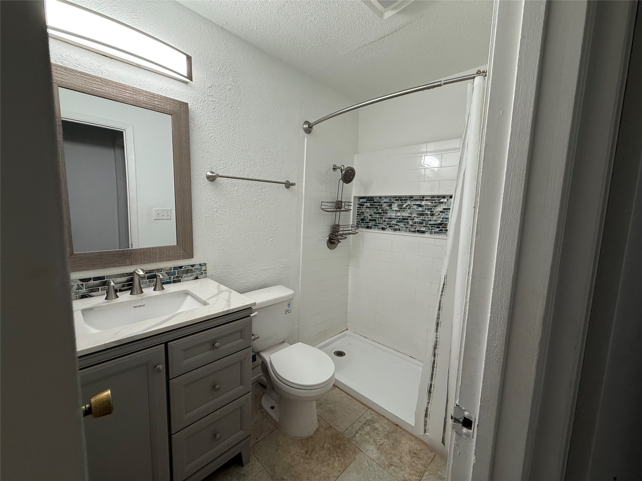906 Silver Quail Lane Austin, TX 78758 - Photo 23 of 33 Bathroom featuring a textured ceiling, a textured wall, a stall shower, and vanity