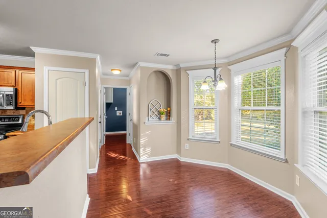 an empty room with wooden floor fireplace and windows