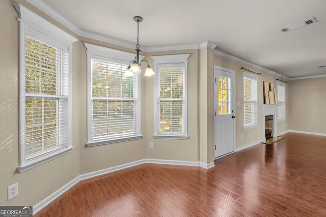 a view of an empty room with wooden floor fireplace and a window