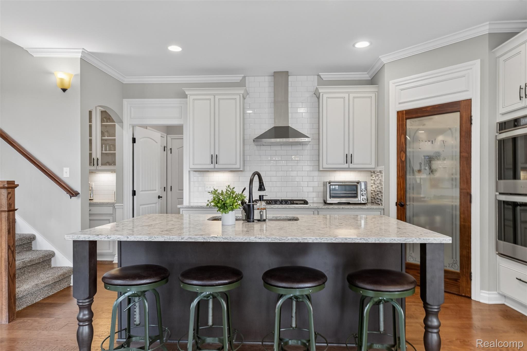 2531 Walnut View Drive Howell, MI 48855 - Photo 16 of 34 Kitchen featuring a large island with granite countertop, white shaker cabinetry, stainless steel appliances, a subway tile backsplash, and wood-finish flooring