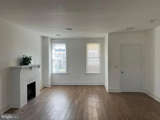 an empty room with windows and fireplace