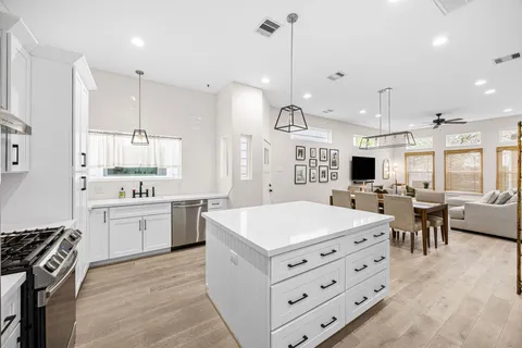 a large kitchen with kitchen island a stove a sink a dining table and chairs