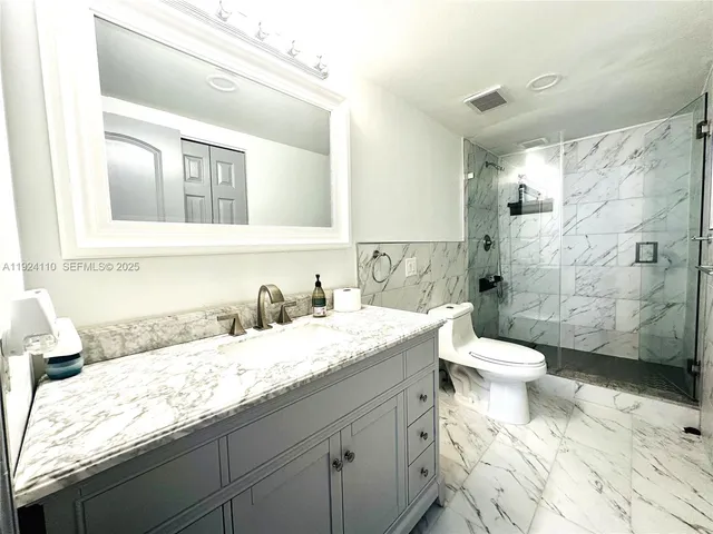 a bathroom with a granite countertop sink mirror vanity and toilet