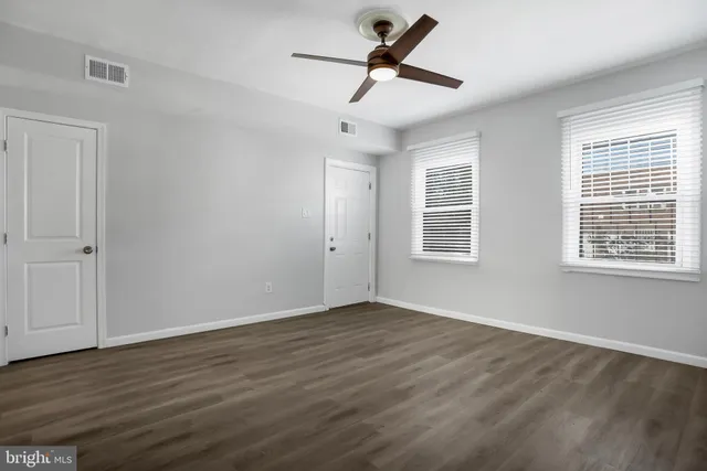 a view of empty room with wooden floor and fan