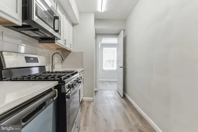 a kitchen with stainless steel appliances granite countertop a stove and a wooden floor